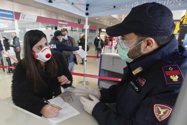 A traveller wears a mask as she fills out a form at a check point set up by border police inside Rome's Termini train station.