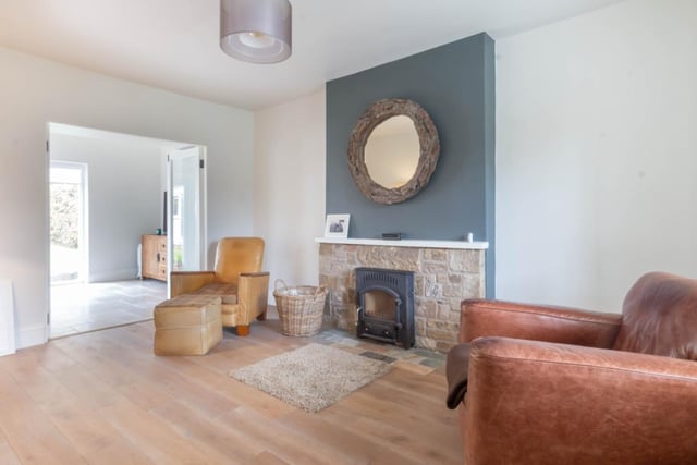 The sitting room has a Rayburn inset to a stone fireplace, solid oak wood flooring and glazed double doors to the garden room.