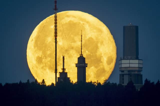 The full moon sets behind the telecommunication devices on top of the Feldberg mountain near Frankfurt, Germany, on June 15 2022. (AP Photo/Michael Probst)