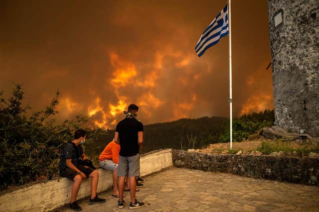 Local residents look at the wildfire approaching the village of Gouves on Evia (Euboea) island, second largest Greek island, on Sunday