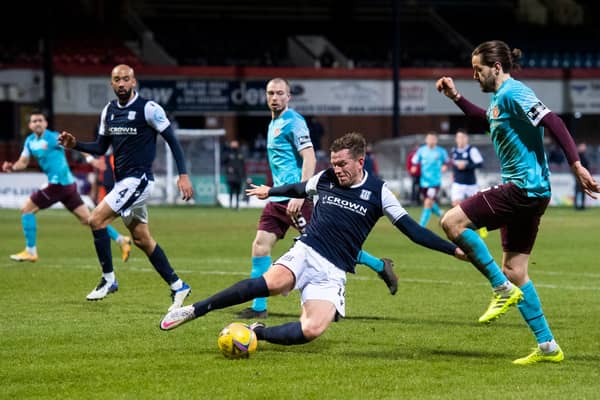 Dundee's Lee Ashcroft slides in on Hearts' Peter Haring at Dens Park.