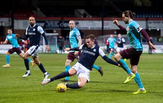 Dundee's Lee Ashcroft slides in on Hearts' Peter Haring at Dens Park.