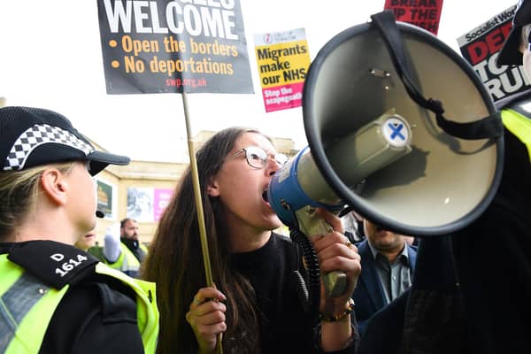 A demonstrator speaks in a loud hailer as she protests against the arrival of the Tory leadership contenders to the Perth hustings on 16 August