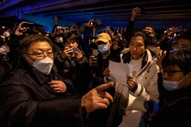 A government official at left speaks to participants in a protest against China's strict zero COVID measures in Beijing, China.