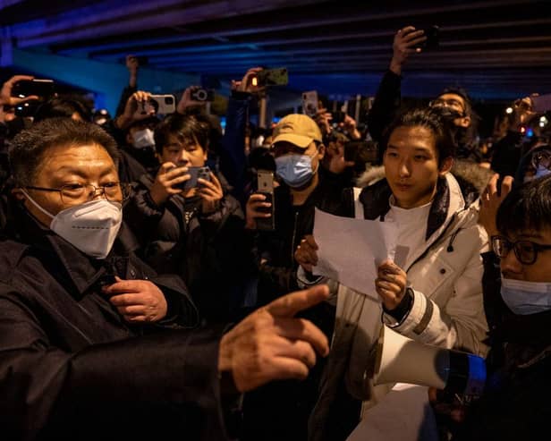 A government official at left speaks to participants in a protest against China's strict zero COVID measures in Beijing, China.