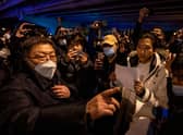 A government official at left speaks to participants in a protest against China's strict zero COVID measures in Beijing, China.