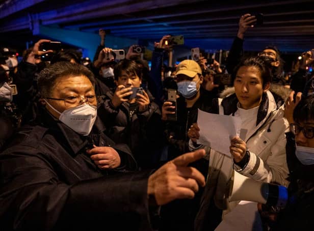 A government official at left speaks to participants in a protest against China's strict zero COVID measures in Beijing, China.