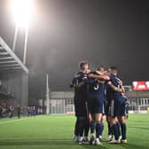 Scotland's forward Lyndon Dykes is mobbed by team-mates after scoring the winning goal.