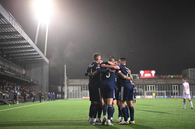 Scotland's forward Lyndon Dykes is mobbed by team-mates after scoring the winning goal.
