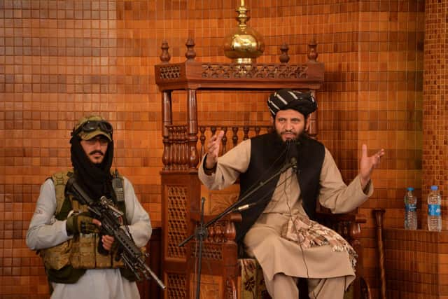 An imam,  guarded by an armed Taliban fighter, speaks during Friday prayers at the Abdul Rahman Mosque in Kabul (Picture: Hoshang Hashimi/AFP via Getty Images)