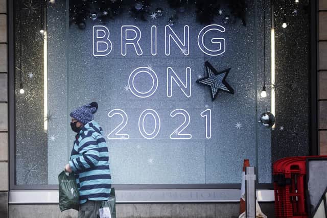A shopper wearing a protective face mask walks past a shop sign that read "Bring On 2021" in Edinburgh