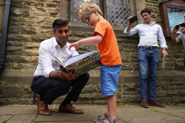 Rishi Sunak looks at a book with Teddy Openshaw as his father, Henry, looks on after a Conservative leadership campaign event in Ribble Valley yesterday (Picture: Owen Humphreys/pool/Getty Images)