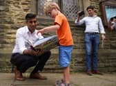 Rishi Sunak looks at a book with Teddy Openshaw as his father, Henry, looks on after a Conservative leadership campaign event in Ribble Valley yesterday (Picture: Owen Humphreys/pool/Getty Images)