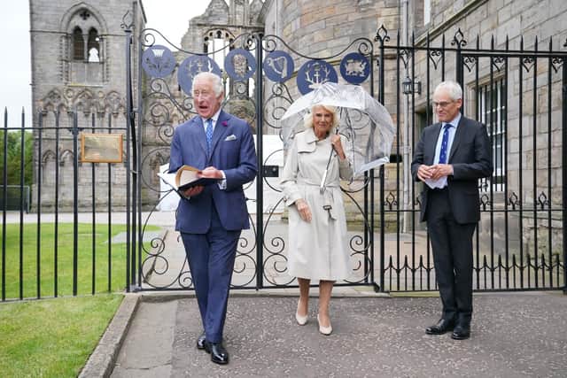 King Charles III and Queen Camilla are presented with a leather-bound book detailing the history of Holyroodhouse by moderator of the High Constables, Roderick Urquhart, as they visit the new Jubilee Gates, installed at the entrance to Abbey Yard. Picture: Jonathan Brady/PA Wire