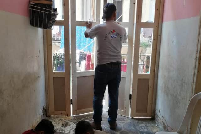 One of the skilled Syrian refugees installs a new door in a flat left badly damaged by the blast.
