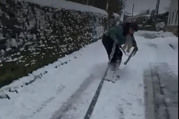 Watch as man goes snowboarding down street during heavy snow as cold weather continues