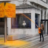 A Just Stop Oil protester spray paints a sign outside New Scotland Yard in London. (Photo: Stefan Rousseau/PA Wire)