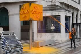 A Just Stop Oil protester spray paints a sign outside New Scotland Yard in London. (Photo: Stefan Rousseau/PA Wire)