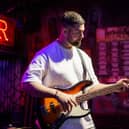 Musician performs on stage at Greene King pub