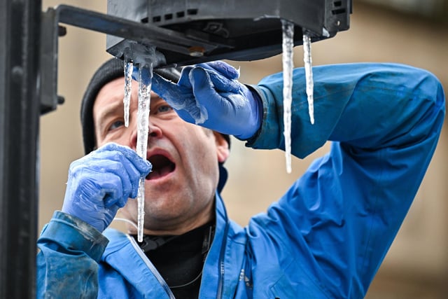 A set designer focuses on placing icicles on Glasgow traffic lights (Photo by Jeff J Mitchell/Getty Images).