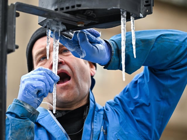 A set designer focuses on placing icicles on Glasgow traffic lights (Photo by Jeff J Mitchell/Getty Images).