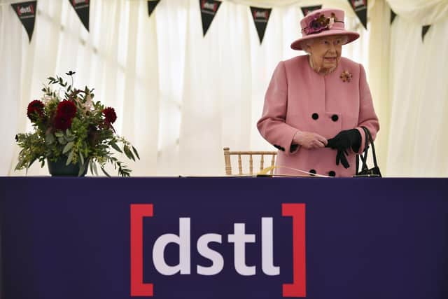 Queen Elizabeth II signing a visitors book during a visit to the Defence Science and Technology Laboratory (DSTL) at Porton Down, Wiltshire.