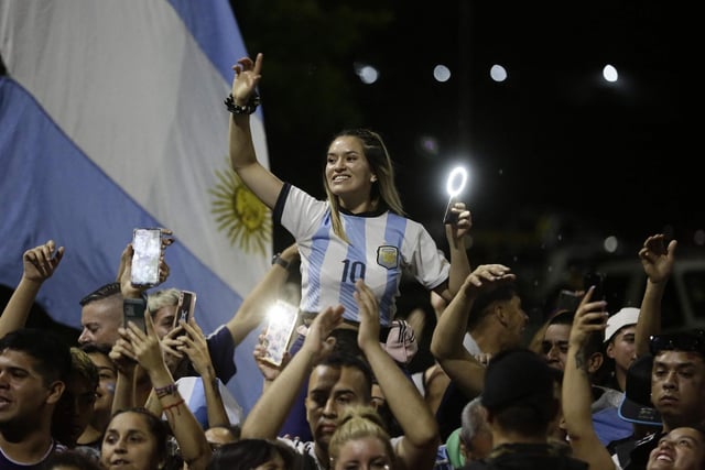 Argentina's supporters cheer Argentina's players as they drive past on board a bus celebrating after winning the Qatar 2022 World Cup tournament as they leave Ezeiza International Airport en route to the Argentine Football Association (AFA) training centre in Ezeiza, Buenos Aires province, Argentina. (Photo by Emiliano Lasalvia / AFP) (Photo by EMILIANO LASALVIA/AFP via Getty Images)