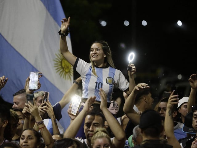Argentina's supporters cheer Argentina's players as they drive past on board a bus celebrating after winning the Qatar 2022 World Cup tournament as they leave Ezeiza International Airport en route to the Argentine Football Association (AFA) training centre in Ezeiza, Buenos Aires province, Argentina. (Photo by Emiliano Lasalvia / AFP) (Photo by EMILIANO LASALVIA/AFP via Getty Images)