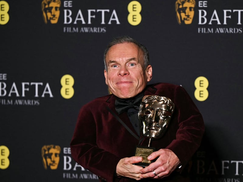 British actor Warwick Davis poses with the BAFTA fellowship Award during the BAFTA British Academy Film Awards ceremony at the Royal Festival Hall