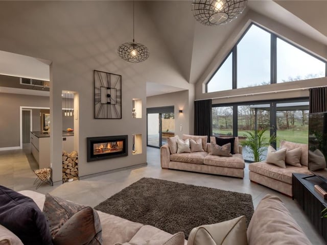 The sitting room has a dual aspect wood burning stove, bi-fold doors to the patio, and a feature back lit wall.
