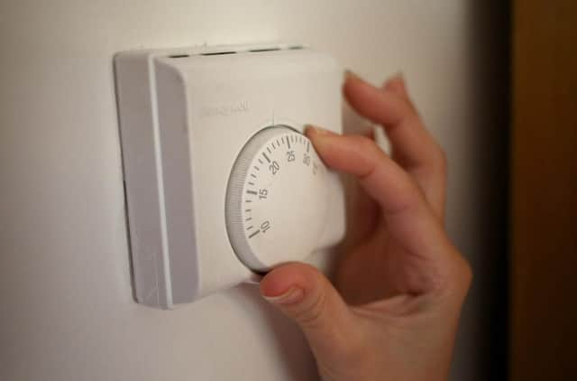 Undated file photo of a person using a central heating thermostat.