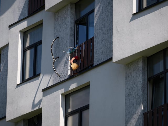 A man cleans the broken glass from the balcony of an apartment following a nearby rocket strike the previous evening. Photo by Leon Neal/Getty Images