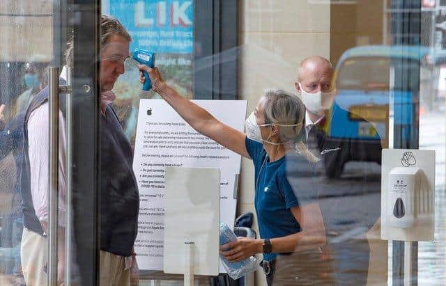 A retail worker takes the temperature of a customer entering the Apple Store on Princes Street.