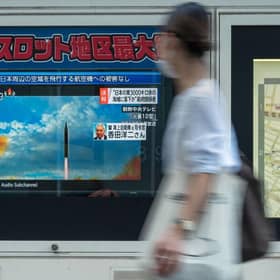 A woman walks past a public television screen in Tokyo, displaying file footage of North Korean missile launches during a broadcast about an early morning North Korean missile launch which prompted an evacuation alert when it flew over northeastern Japan.