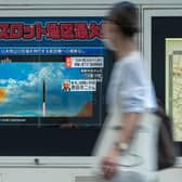 A woman walks past a public television screen in Tokyo, displaying file footage of North Korean missile launches during a broadcast about an early morning North Korean missile launch which prompted an evacuation alert when it flew over northeastern Japan.