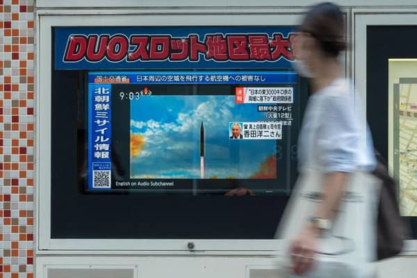 A woman walks past a public television screen in Tokyo, displaying file footage of North Korean missile launches during a broadcast about an early morning North Korean missile launch which prompted an evacuation alert when it flew over northeastern Japan.