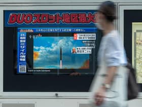 A woman walks past a public television screen in Tokyo, displaying file footage of North Korean missile launches during a broadcast about an early morning North Korean missile launch which prompted an evacuation alert when it flew over northeastern Japan.