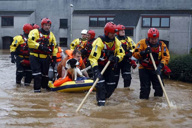 Members of the coastguard rescue team wade through the flood waters to evacuate a man and a dog in Brechin. Picture: Jeff J Mitchell/Getty Images