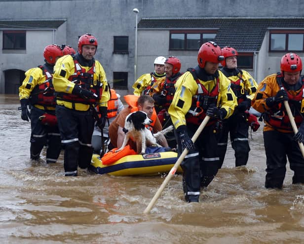 Members of the coastguard rescue team wade through the flood waters to evacuate a man and a dog in Brechin. Picture: Jeff J Mitchell/Getty Images