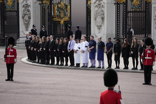 Buckingham Palace staff stand outside its gates ahead of the funeral procession of Queen Elizabeth II. Picture date: Monday September 19, 2022.