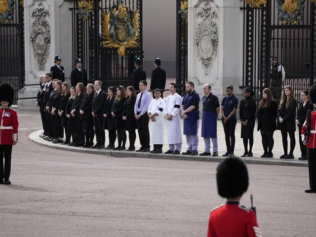 Buckingham Palace staff stand outside its gates ahead of the funeral procession of Queen Elizabeth II. Picture date: Monday September 19, 2022.