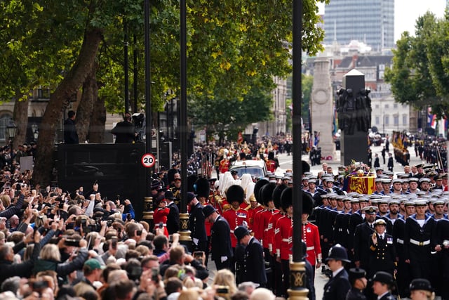 Crowds watch as the State Gun Carriage carries the coffin of Queen Elizabeth II, draped in the Royal Standard with the Imperial State Crown and the Sovereign's orb and sceptre, in the Ceremonial Procession following her State Funeral at Westminster Abbey, London. Picture date: Monday September 19, 2022.