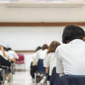 School students writing answer doing exam in classroom