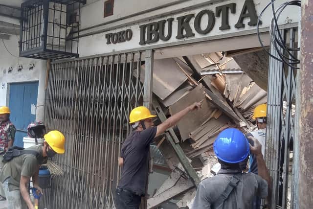 Workers inspect a store damaged during an earthquake in Cianjur, West Java, Indonesia, Monday, Nov. 21, 2022. An earthquake shook Indonesia's main island of Java on Monday damaging dozens of buildings and sending residents into the capital's streets for safety. (AP Photo/Firman Taqur)