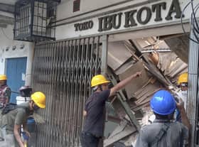Workers inspect a store damaged during an earthquake in Cianjur, West Java, Indonesia, Monday, Nov. 21, 2022. An earthquake shook Indonesia's main island of Java on Monday damaging dozens of buildings and sending residents into the capital's streets for safety. (AP Photo/Firman Taqur)