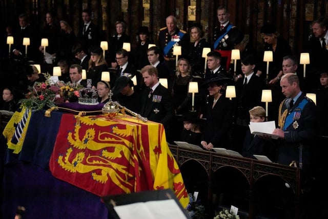 Members of the royal family (front row, left to right) Lena Tindall, Zara Tindall, Mia Tindall, the Duchess of Sussex, the Duke of Sussex, Princess Charlotte, the Princess of Wales, Prince George, and the Prince of Wales, stand for the coffin of Queen Elizabeth II, draped in the Royal Standard with the Imperial State Crown and the Sovereign's orb and sceptre, during the Committal Service at St George's Chapel in Windsor Castle, Berkshire. Picture date: Monday September 19, 2022.