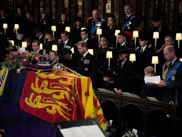 Members of the royal family (front row, left to right) Lena Tindall, Zara Tindall, Mia Tindall, the Duchess of Sussex, the Duke of Sussex, Princess Charlotte, the Princess of Wales, Prince George, and the Prince of Wales, stand for the coffin of Queen Elizabeth II, draped in the Royal Standard with the Imperial State Crown and the Sovereign's orb and sceptre, during the Committal Service at St George's Chapel in Windsor Castle, Berkshire. Picture date: Monday September 19, 2022.