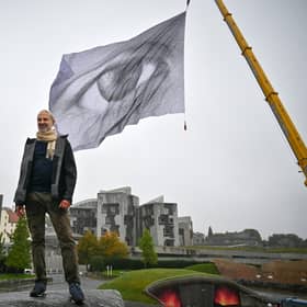 The massive We Are Watching artwork has been hoisted near the Scottish Parliament in Edinburgh as part of a tour that will see it flying in Glasgow during the United Nations climate summit COP26