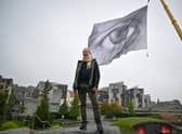 The massive We Are Watching artwork has been hoisted near the Scottish Parliament in Edinburgh as part of a tour that will see it flying in Glasgow during the United Nations climate summit COP26