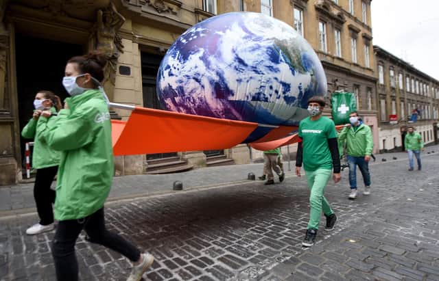 Greenpeace activists carry a giant balloon representing planet Earth  (Photo by DENIS LOVROVIC/AFP via Getty Images)